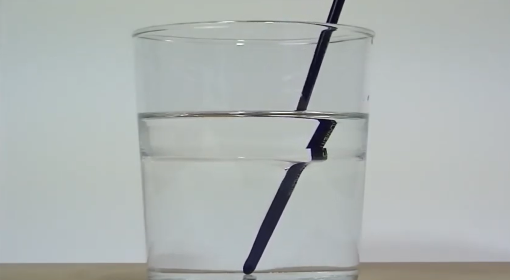 Lápiz en un vaso de agua, refractando la luz